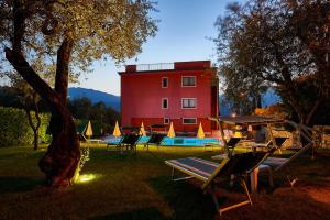 un edificio rojo con un grupo de sillas y una piscina en Residence Hotel Vacanze 2000 - Adults Only, en Malcesine