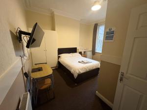 a small room with a bed and a television at Runcorn Jubilee Guest House in Runcorn
