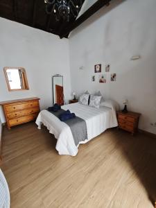 a bedroom with a large white bed and wooden floors at Casa del Drago in Vega de San Mateo