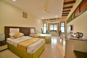 a hotel room with two beds and a desk at Hotel Royal Embassy in Bhilwara