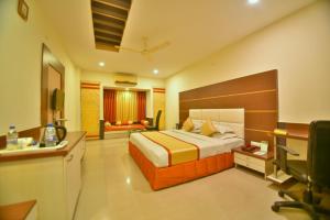 a hotel room with a bed and a desk at Hotel Royal Embassy in Bhilwara +3 photos