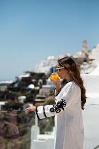 a woman eating a piece of food on top of a building at Ventus Paradiso Villa in Imerovigli