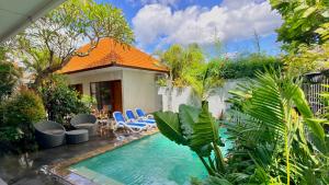 a swimming pool with chairs and a house at Moonlight Sanur in Sanur