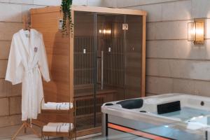 a bathroom with a bath tub and a robe at מילה בוטיק - סוויטה מהממת עם 2 חדרי שינה, מתחם מקורה עם בריכה מחוממת, ג'קוזי ספא וסאונה! in ‘Ein Ya‘aqov