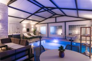 a living room with a pool with tables and chairs at מילה בוטיק - סוויטה מהממת עם 2 חדרי שינה, מתחם מקורה עם בריכה מחוממת, ג'קוזי ספא וסאונה! in ‘Ein Ya‘aqov +13 photos