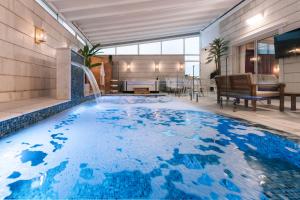 a pool with a waterfall in a hotel room at מילה בוטיק - סוויטה מהממת עם 2 חדרי שינה, מתחם מקורה עם בריכה מחוממת, ג'קוזי ספא וסאונה! in ‘Ein Ya‘aqov