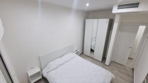 a white bedroom with a bed and a mirror at MAG - Rooms and Apartment in Castelpoto