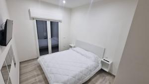 a white bedroom with a bed and a window at MAG - Rooms and Apartment in Castelpoto