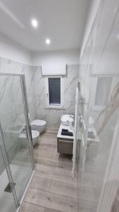 a white bathroom with a toilet and a sink at MAG - Rooms and Apartment in Castelpoto