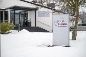 a sign in the snow in front of a building at Hotel Haus Hohne in Hohne