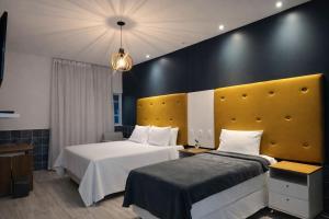 a hotel room with two beds and a yellow headboard at Hotel Summer Beach Paripueira Maceió in Paripueira +99 photos