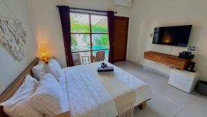 a bedroom with a bed and a tv and a window at Moonlight Sanur in Sanur +11 photos