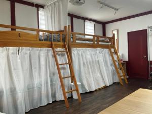 a bedroom with two bunk beds with white curtains at Dormitory JiccA NO HOTEL in Takemiya