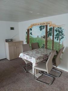a table and chairs with a painting on the wall at Haus Angermann in Struppen