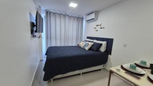 a bedroom with a bed and a tv and a table at Apartamento Maré Alta in Tamandaré