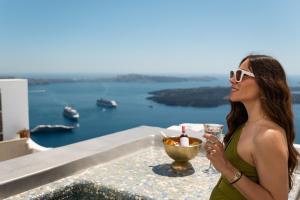 a woman standing on a ledge with a glass of wine at Ventus Paradiso Villa in Imerovigli