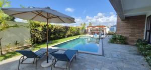 an umbrella and chairs next to a swimming pool at Apartamento Maré Alta in Tamandaré