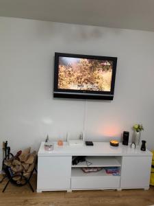 a tv on a white wall with a white desk at Vikendica Rujiste in Mostar