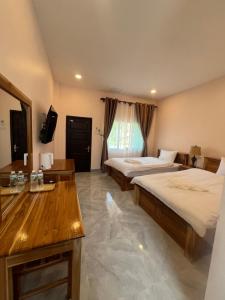 a hotel room with two beds and a television at Leego Hotel in Luang Prabang