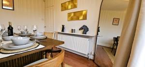a dining room with a table with plates and wine glasses at Spacious Home Near Wembley, Free Parking, Close to Tube, Garden in Pinner