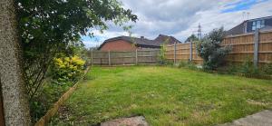 a backyard with a fence and a grass yard at Spacious Home Near Wembley, Free Parking, Close to Tube, Garden in Pinner