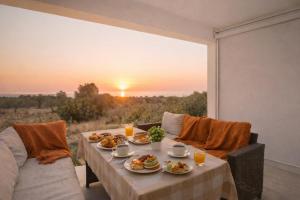 a table with food on it with a view of the sunset at Exclusive Olive & Herb Villa, Mountain to Sea Views, Rhodes in Afantou