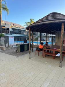 two people sitting at a picnic table under an umbrella at Manduhra Motel Resort in Mandurah