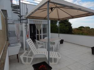patio con tavolo, sedie e ombrellone di Otranto Green House a Otranto