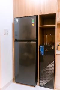 a black refrigerator in a kitchen next to a shelf at RubyHome in Thôn Nguyệt Biều