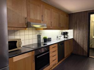 a kitchen with wooden cabinets and a sink and a microwave at Cozy Couples or Family Retreat - Hemsedal in Hemsedal