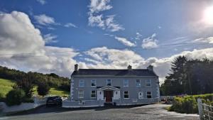 a large white house with a blue sky and clouds at The Serendipity Suite - A Scenic Countryside Hideaway in Letterkenny