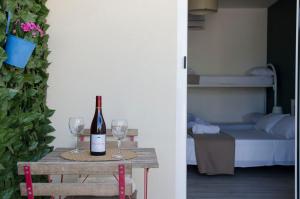 a bottle of wine sitting on a table with two glasses at Residence La Perla - Marzamemi & Sea - Homie Livings in Marzamemi +80 photos