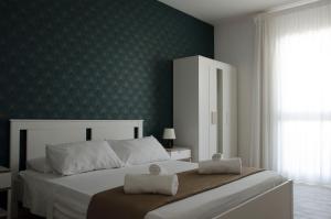 a bedroom with a bed with a green wall at Residence La Perla - Marzamemi & Sea - Homie Livings in Marzamemi