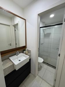 a bathroom with a white sink and a toilet at Apartamento Moderno uma quadra do mar in Vila Velha
