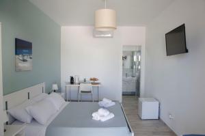 a white bedroom with a large bed and a kitchen at Residence La Perla - Marzamemi & Sea - Homie Livings in Marzamemi