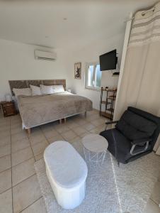 a bedroom with a bed and a couch and a chair at Logement cosy avec piscine chauffée, jacuzzi, jardin et climatisation in Flayosc +72 photos
