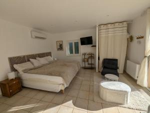 a bedroom with a large bed and a chair at Logement cosy avec piscine chauffée, jacuzzi, jardin et climatisation in Flayosc