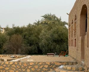 a bench sitting next to a building with trees at Bandres farm in Siwa