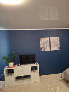 a room with a desk with a tv on a blue wall at Jelena Apartment 69 in Rēzekne +15 photos