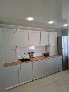 a white kitchen with white cabinets and a sink at Jelena Apartment 69 in Rēzekne