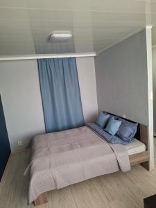a small bedroom with a bed with blue pillows at Jelena Apartment 69 in Rēzekne