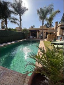 a swimming pool in front of a house with palm trees at VILLA DETENTE PISCINE PRIVEE PROCHE D'AGADlR in Taroudant