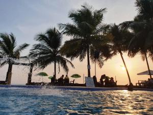 a resort swimming pool with palm trees and people sitting at Bamboo Beach Resorts in Paynesville +2 photos