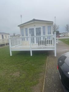 a large white house with a porch and a car at 2 Bedroom caravan in Saint Osyth
