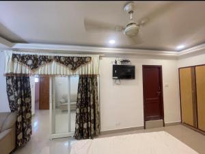a room with a bed and a tv and curtains at SangeethaInn in Ongole