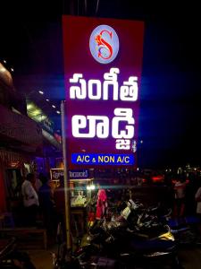 a sign for a store with motorcycles parked next to it at SangeethaInn in Ongole