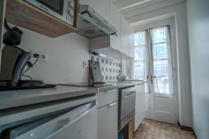 a white kitchen with a sink and a window at Le gîte de Agnes in Fronsac