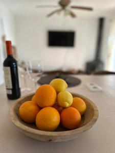 a bowl of oranges and lemons with a bottle of wine at Cortijo Chupito in Yunquera