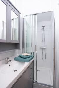 a white bathroom with a shower and a sink at La Calade Charming Apartment in Nîmes