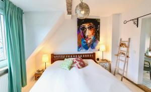 a bedroom with a white bed with a painting on the wall at Schuhmacherei Rooms in Oestrich-Winkel